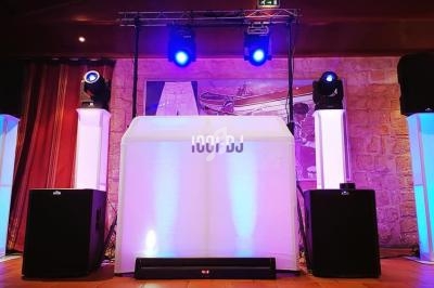 Installation de matériel de sonorisation et éclairage avec une table de DJ illuminée dans une salle en pierre.