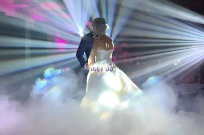 Un couple danse dans une ambiance féérique avec des faisceaux lumineux et un sol couvert de fumée.