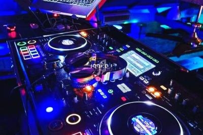 Table de mixage DJ avec platines lumineuses et un ordinateur portable affichant une interface musicale.