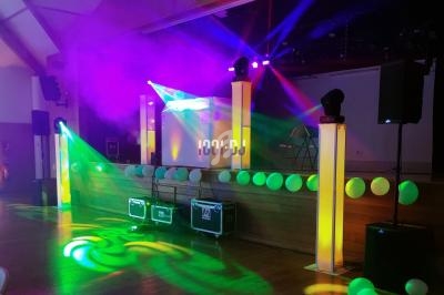 Jeu de lumières colorées sur une scène décorée de ballons, avec des équipements audio visibles au sol.