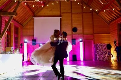 Un couple danse dans une salle en bois illuminée par des guirlandes et des projecteurs colorés.