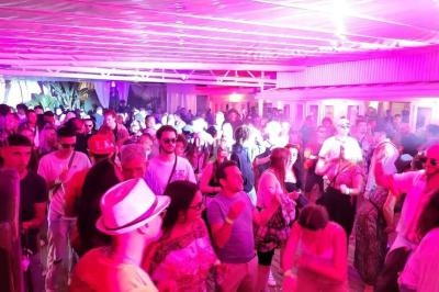 Foule de personnes dans une ambiance festive sous un éclairage rose, rassemblées dans un espace couvert.