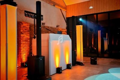 Installation de matériel de sonorisation et d'éclairage dans une salle avec murs en briques et lumière tamisée.