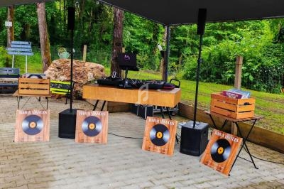 Stand de DJ en plein air avec platines vinyles, enceintes et caisses en bois, entouré de verdure.
