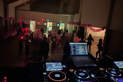 Un DJ mixant de la musique sur une table de mixage éclairée par des lumières colorées dans une ambiance sombre.