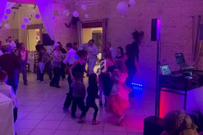 Des invités dansent dans une salle décorée de guirlandes et lumières colorées lors d'une fête ou d'un événement.