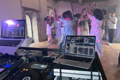 Vue d'une piste de danse animée lors d'une fête, avec des équipements de DJ au premier plan.