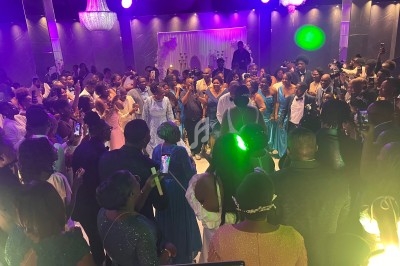 Groupe de personnes dansant et célébrant lors d'un événement festif dans une salle éclairée par des lumières colorées.