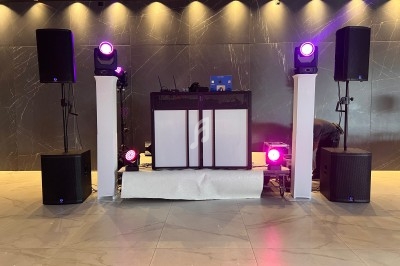 Installation de matériel de sonorisation et d'éclairage avec une table de mixage dans une salle au mur sombre.