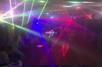 Salle sombre avec des jeux de lumière colorés et des personnes dansant sur une piste.