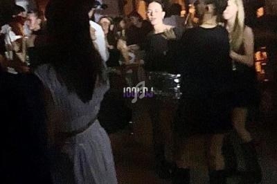 Personnes dansant et discutant dans une ambiance tamisée lors d'une soirée avec décoration suspendue.