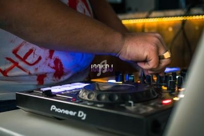 Un DJ ajuste les commandes d'une table de mixage Pioneer dans un environnement faiblement éclairé.