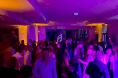 Groupe de personnes dansant dans une salle éclairée par des lumières violettes et jaunes.