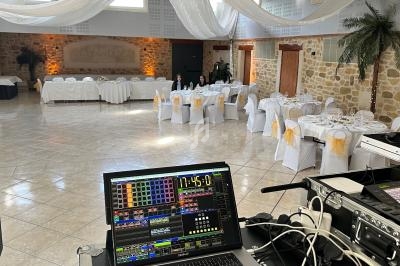 Salle de réception décorée avec des tables dressées, vue depuis une console de mixage audio et vidéo.