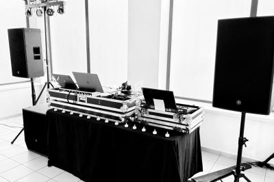 Équipement de DJ avec table de mixage, ordinateurs portables et enceintes dans une salle lumineuse.