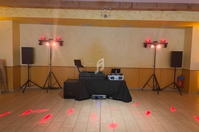 Installation de matériel de sonorisation et d'éclairage dans une salle avec des spots rouges projetés au sol.