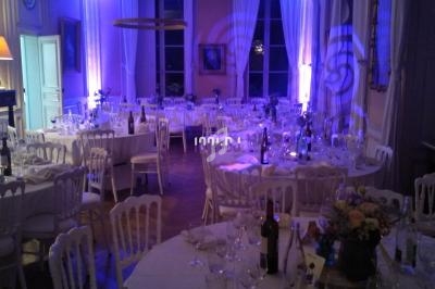 Salle de réception élégamment décorée avec des tables rondes dressées, éclairage tamisé et ambiance lumineuse bleutée.
