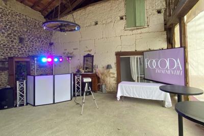 Table de mixage éclairée avec des lumières colorées, un ordinateur affichant un logiciel de DJ en arrière-plan.