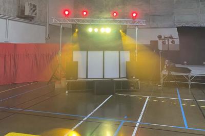 Table de mixage éclairée avec des lumières colorées, un ordinateur affichant un logiciel de DJ en arrière-plan.