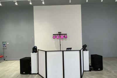 Table de mixage éclairée avec des lumières colorées, un ordinateur affichant un logiciel de DJ en arrière-plan.