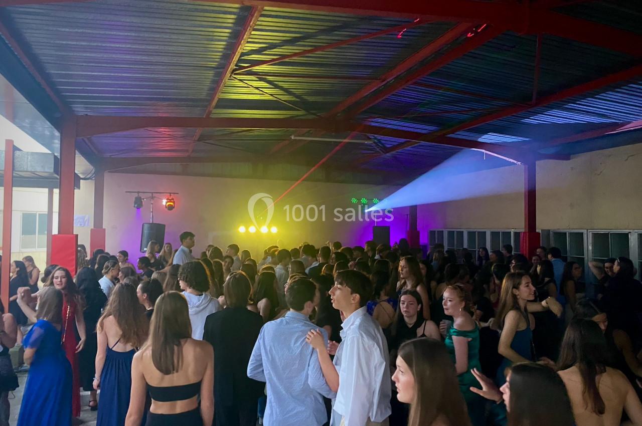 Groupe de jeunes dans une salle couverte, éclairée par des lumières colorées, lors d'une soirée dansante.