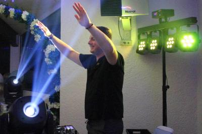 Table de mixage éclairée avec des lumières colorées, un ordinateur affichant un logiciel de DJ en arrière-plan.