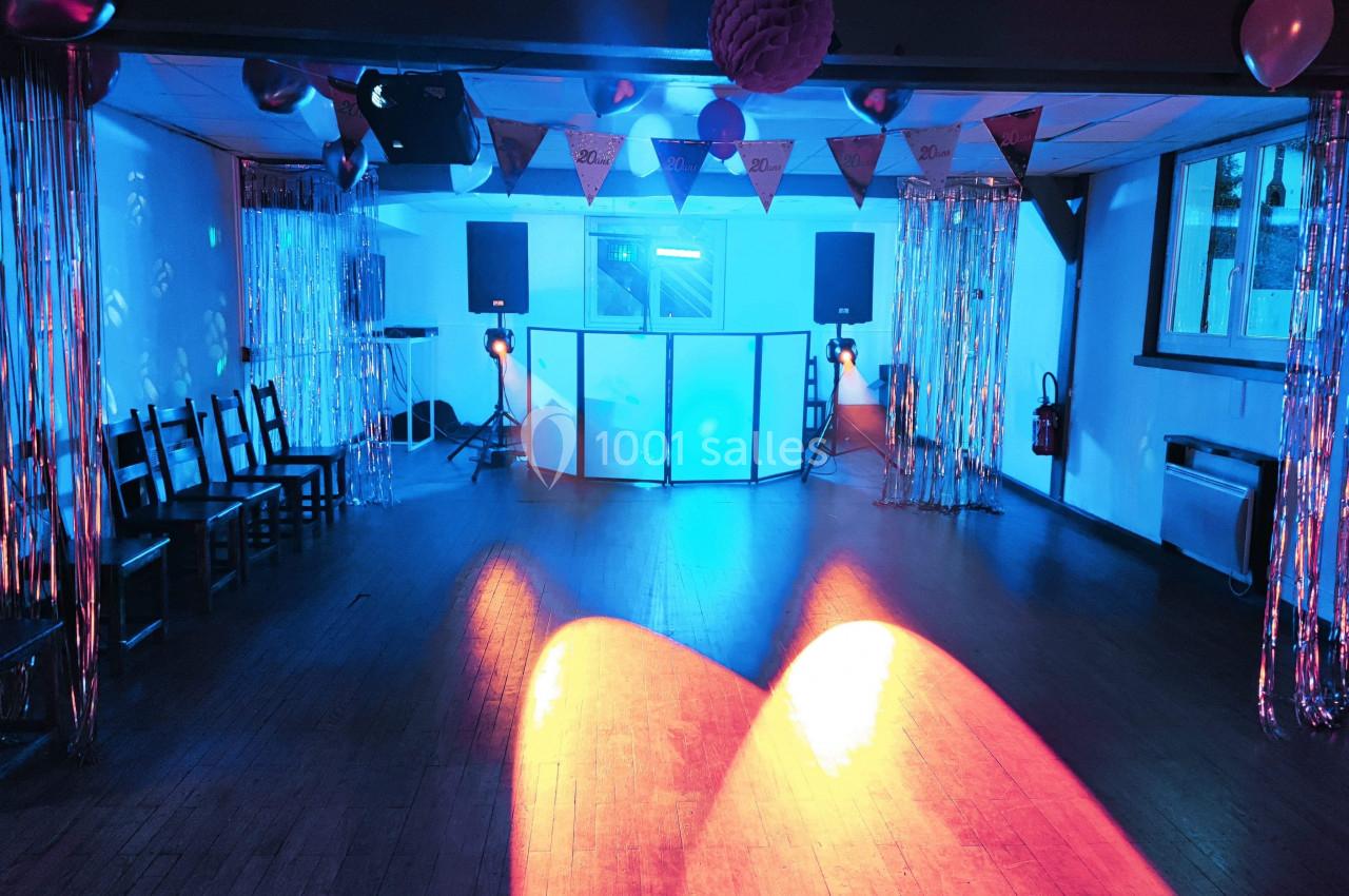 Salle de fête décorée avec guirlandes, éclairage coloré et équipement de sonorisation installé au centre.