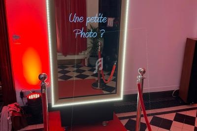 Miroir interactif lumineux avec inscription ’Une petite photo ?’ sur tapis rouge, entouré de poteaux et cordons.