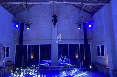 Salle avec éclairage bleu, murs en pierre, plafond en bois et miroir reflétant des tables et des chaises.