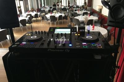 Console DJ Pioneer installée dans une salle de réception avec tables dressées et décorations en arrière-plan.