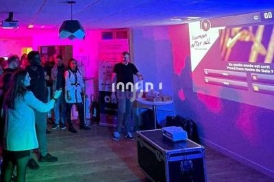 Des personnes participent à un quiz interactif projeté sur un mur dans une salle éclairée par des lumières colorées.