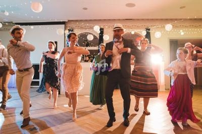 Des personnes dansent en groupe sur une piste éclairée, décorée de guirlandes lumineuses et de lanternes suspendues.