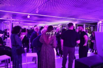Groupe de personnes discutant dans un espace intérieur éclairé par des lumières violettes.