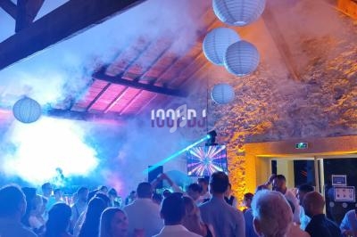 Salle en pierre avec éclairage coloré, DJ sur scène, écrans lumineux et invités dansant sous des lanternes suspendues.