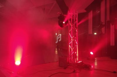 Éclairage de scène rouge avec projecteurs et fumée dans une salle intérieure.