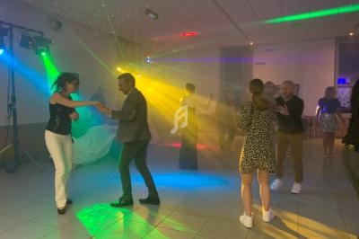 Personnes dansant sous des lumières colorées dans une salle sombre lors d'une soirée festive.