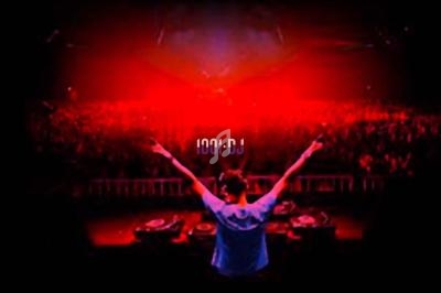 Un DJ vu de dos, bras levés, face à une foule dans une ambiance lumineuse rouge.