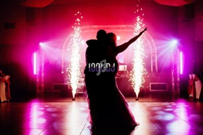 Un couple danse sur une piste éclairée par des lumières colorées et des étincelles en arrière-plan.