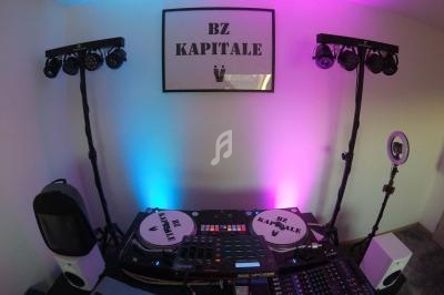 Équipement de DJ avec platines, table de mixage et éclairages colorés dans une pièce décorée.