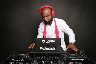 Un DJ portant un casque rouge mixe de la musique sur une table de mixage avec un ordinateur portable.