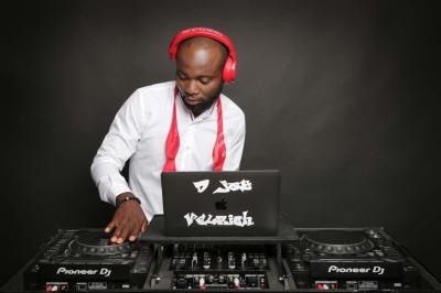 Un DJ portant un casque rouge mixe de la musique sur une table de mixage avec un ordinateur portable.