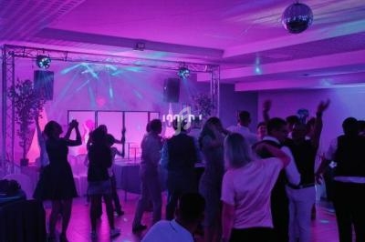 Personnes dansant dans une salle éclairée par des lumières colorées, avec une piste et une ambiance festive.