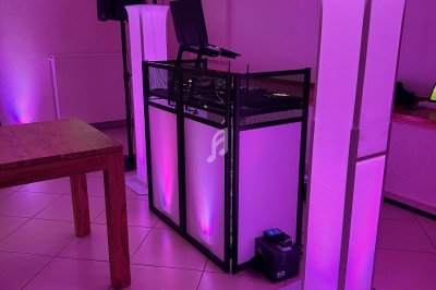 Installation de matériel de DJ avec éclairage LED rose dans une salle au sol carrelé et murs clairs.