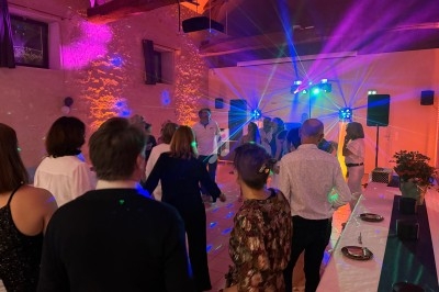 Des personnes dansent sous des jeux de lumière colorés dans une salle aux murs en pierre.