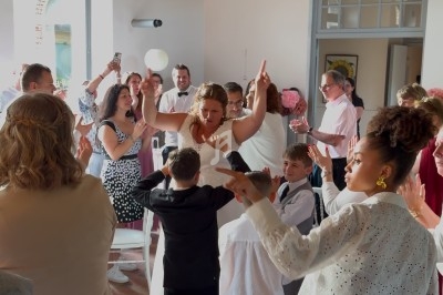 Des personnes dansent joyeusement dans une salle lumineuse avec des murs blancs et de grandes fenêtres.