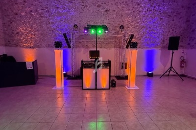 Installation de matériel de sonorisation et éclairage coloré dans une salle avec murs en pierre et sol carrelé.