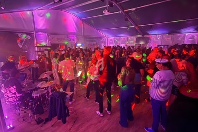 Des personnes dansent sous des lumières colorées dans une salle avec un groupe de musique jouant sur scène.