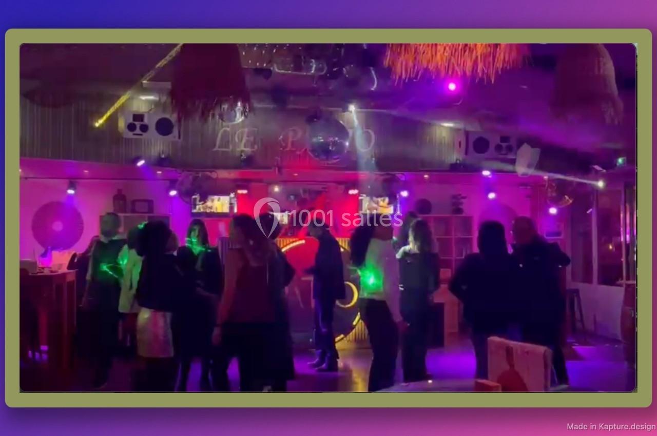 Personnes dansant dans un club éclairé par des lumières colorées, ambiance festive et conviviale.