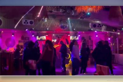 Personnes dansant dans une ambiance festive avec des lumières colorées, vue depuis une table de mixage de DJ.