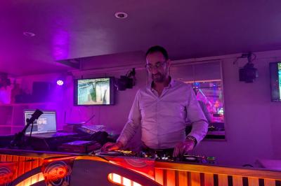 Personnes dansant dans une salle sombre éclairée par des lumières colorées, ambiance festive.